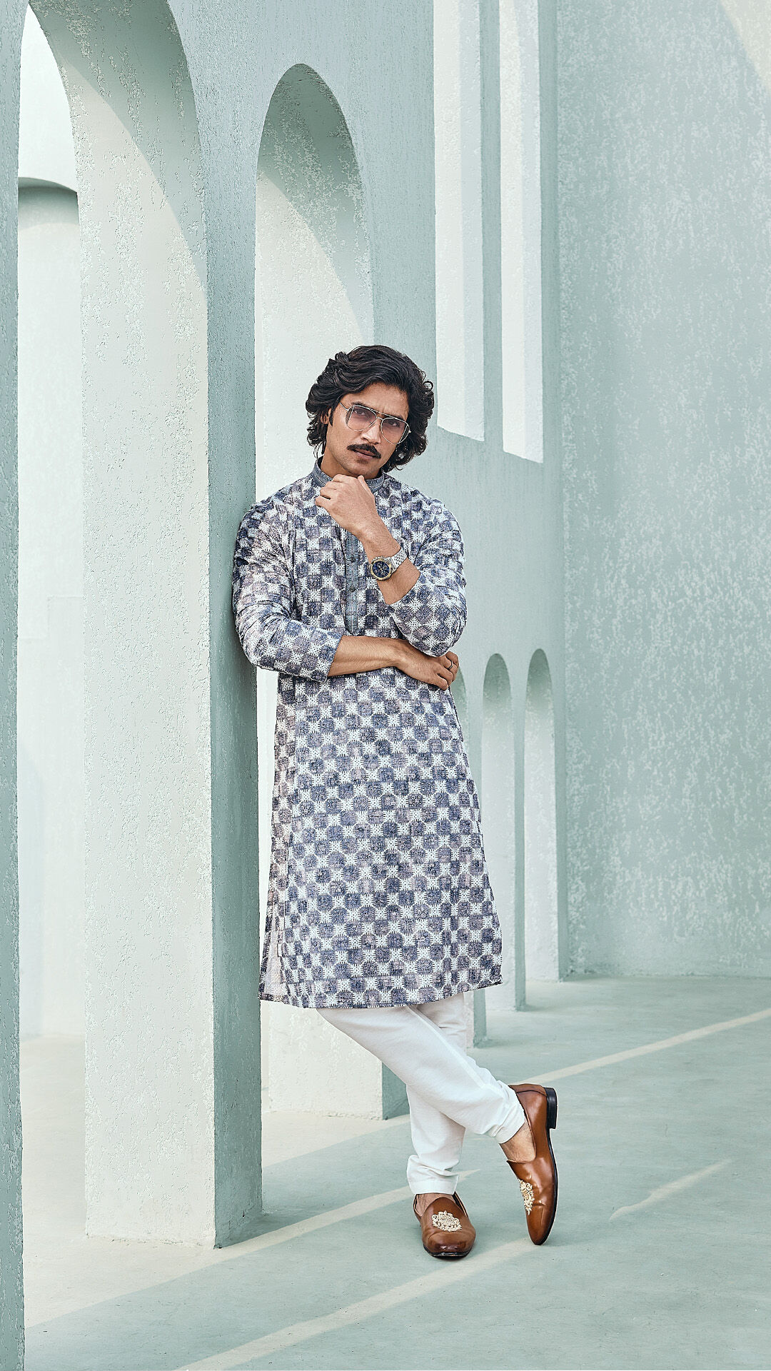 A groom sporting a purple floral kurta and pajama set, paired with brown juttis for a chic yet relaxed wedding look